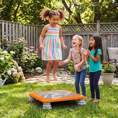 The kids trampoline set up on a green lawn with three children playing together outside