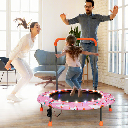 A pink kids trampoline with LED lights being used by a family indoors