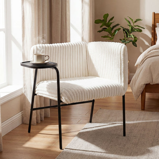 The accent chair placed in a bedroom next to a window with a steaming cup on the tray table