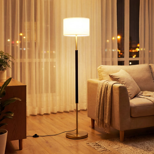 The modern floor lamp in a living room next to a sofa, lit up at night