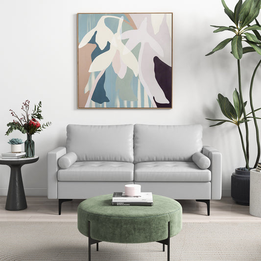 Light grey sofa couch in a modern living room with a green ottoman and artwork
