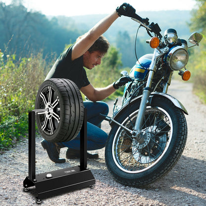 Man using the motorcycle wheel balancer with adjustable centering cones to balance a motorcycle wheel outdoors