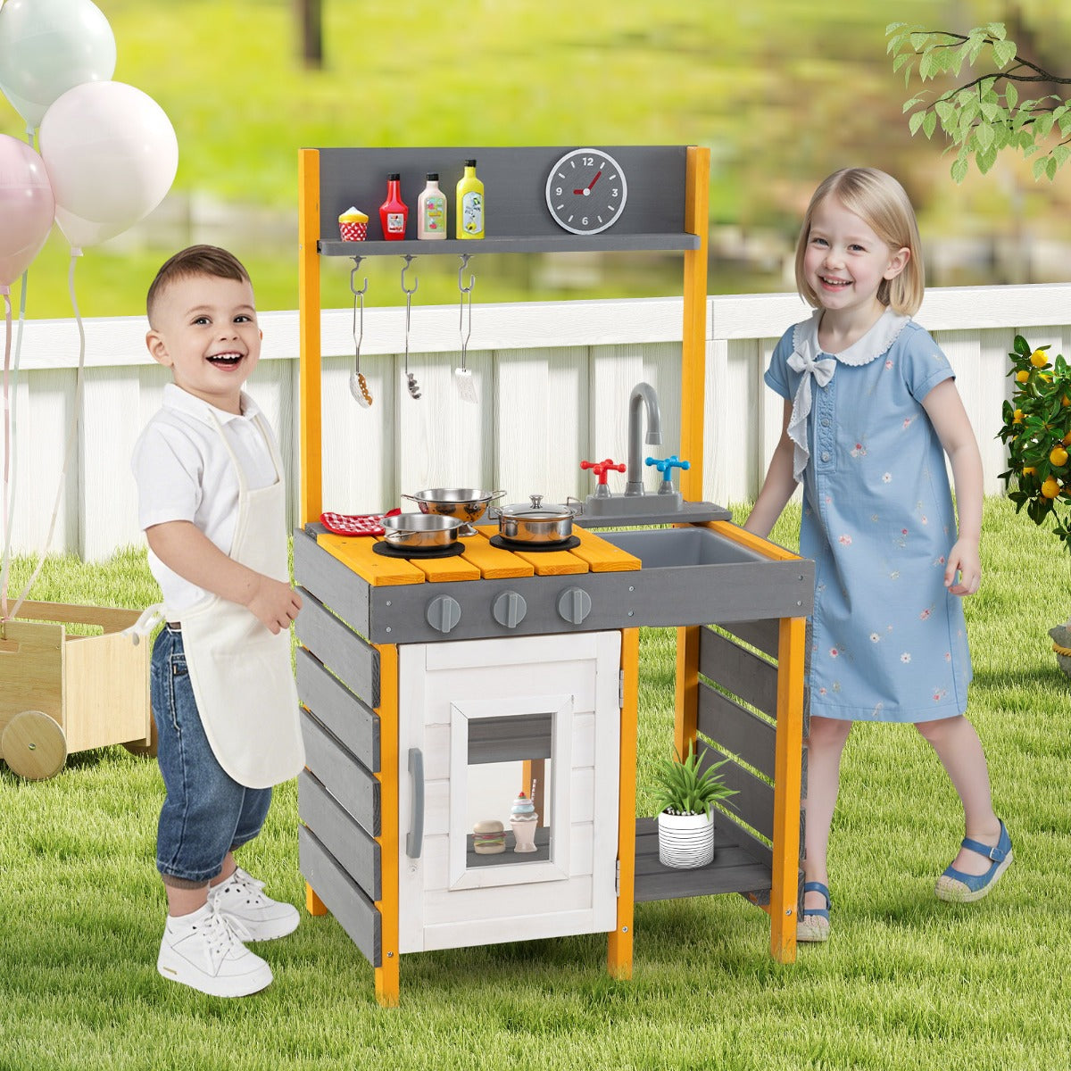 Two children playing with the grey mud kitchen set in a garden