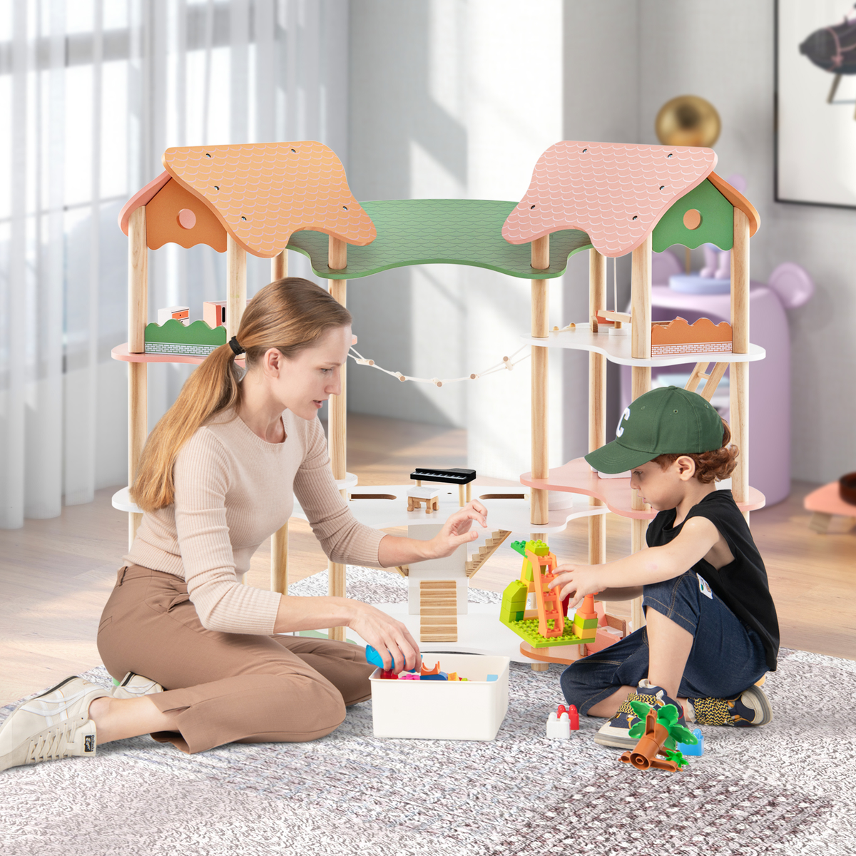 A mother and son sitting on a rug and playing with the wooden playhouse together