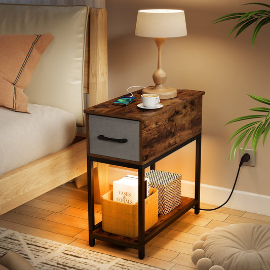 The end & side table is shown next to a bed with a lamp and phone charging