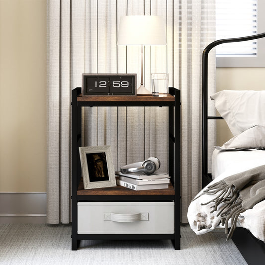 The bedside table with a lamp, picture frame and books on the top shelf and a fabric drawer below