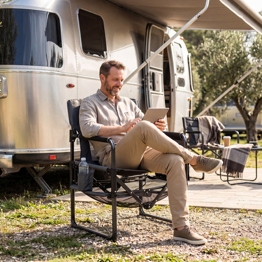 The camping furniture being used by a man sitting outside a caravan with a tablet
