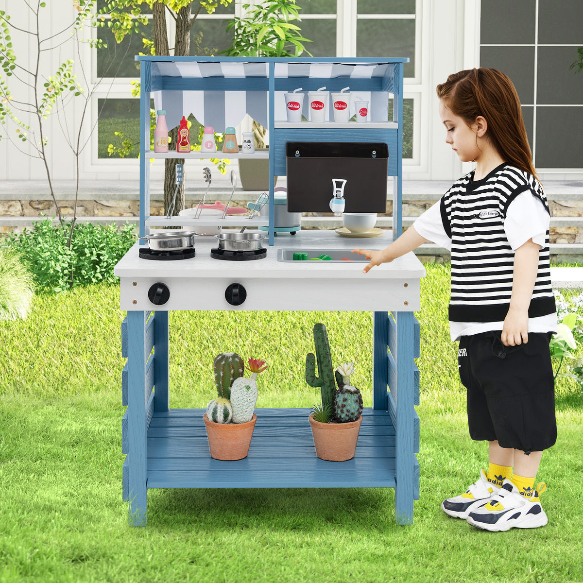 The play kitchen set standing on a lawn with a child playing at the sink area