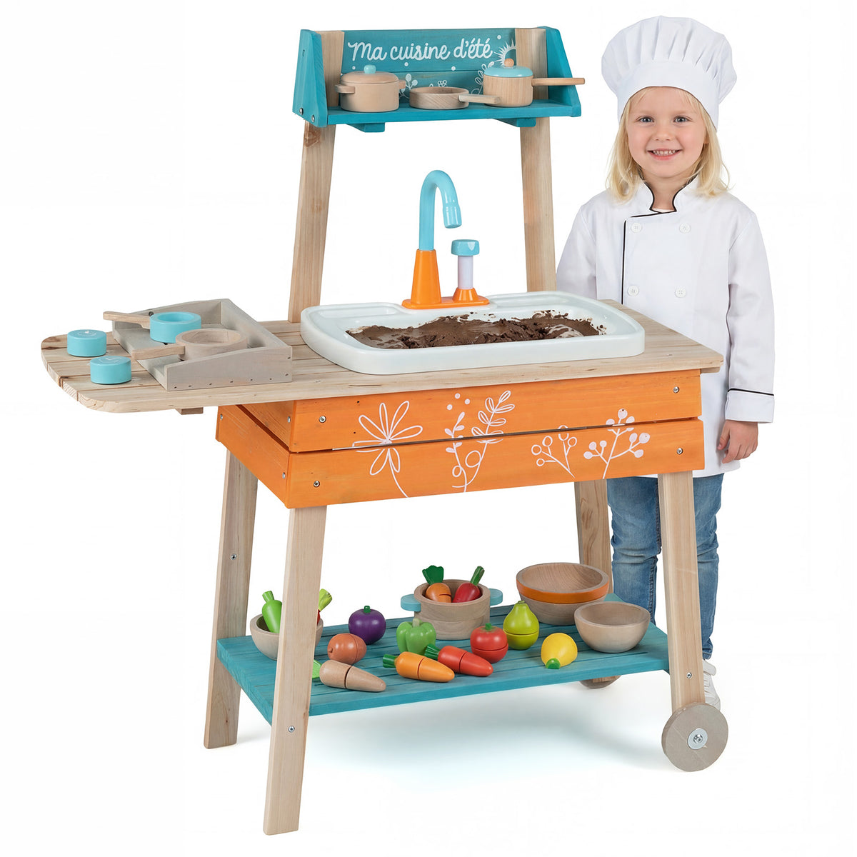 A young girl dressed as a chef standing next to the wooden play kitchen set