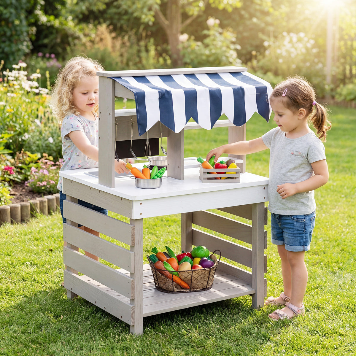 Two children playing together with the play kitchen set in a grassy outdoor area