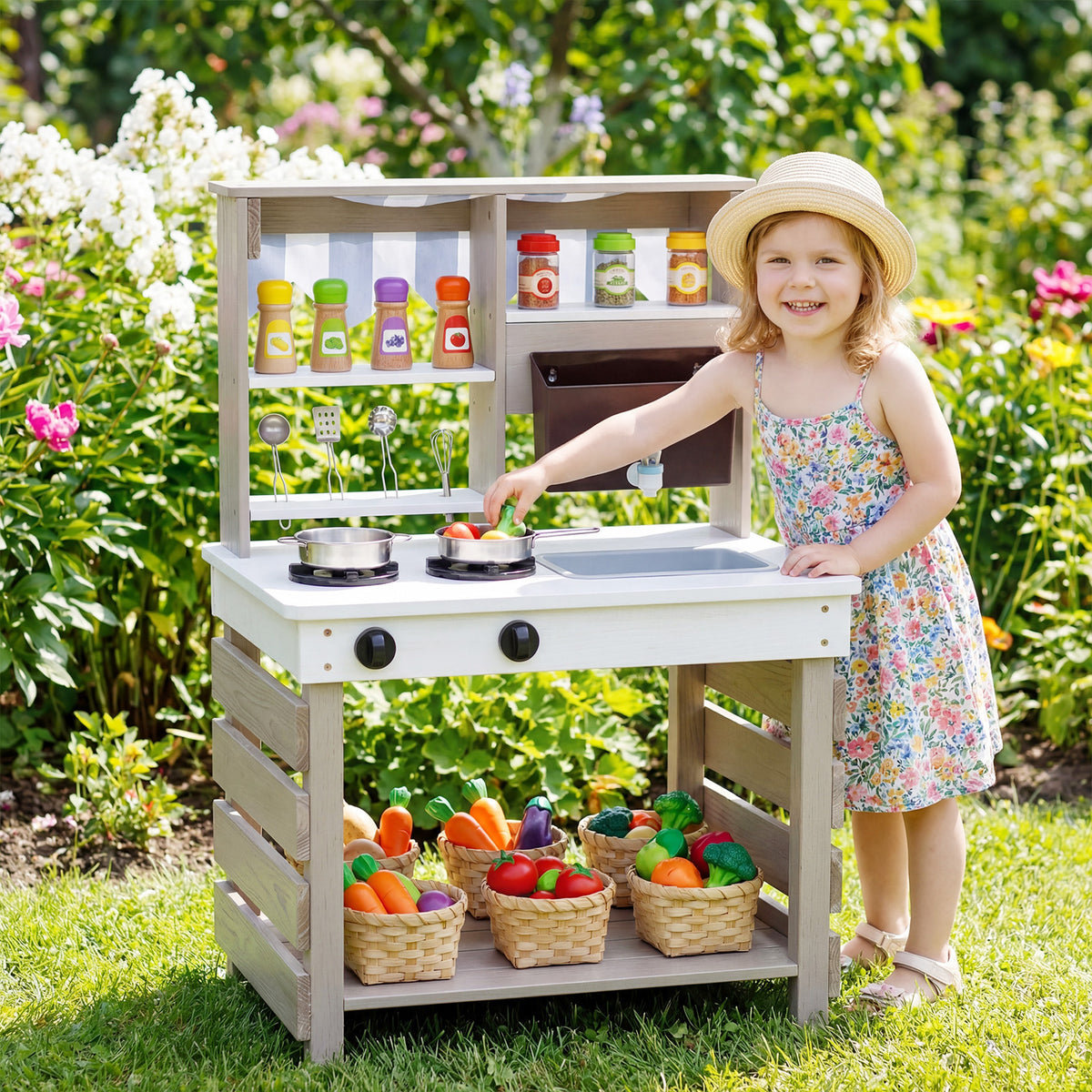 The play kitchen set standing in a sunny garden with a young girl playing with the toy vegetables