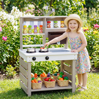 The play kitchen set standing in a sunny garden with a young girl playing with the toy vegetables