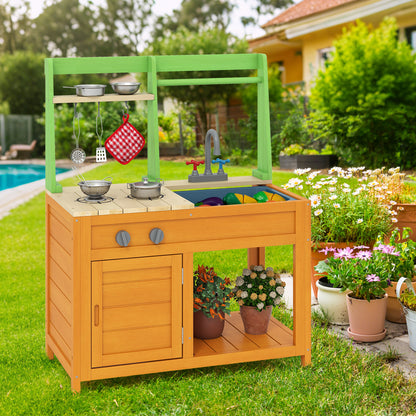 The outdoor play kitchen set in a garden setting next to a swimming pool, with plants and flowers around it