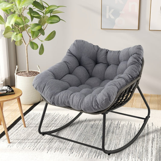 The grey patio rocking chair with a thick cushion, shown with a potted plant and a small side table