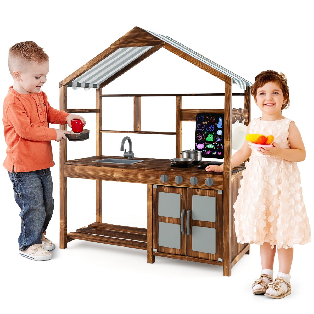 A boy and girl play together with the wooden play kitchen set outdoors