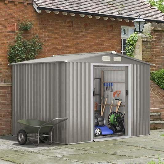The garden shed placed on a patio with gardening tools and a wheelbarrow stored inside
