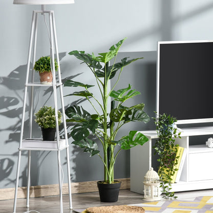 The artificial cheese plant is shown in a modern living room setting next to a television and a floor lamp