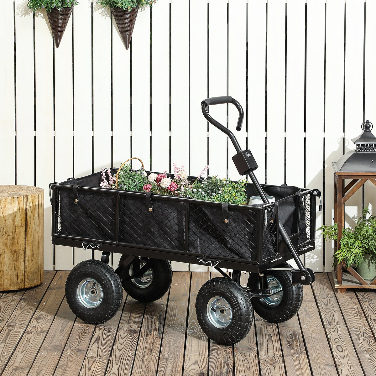 Black garden trolley filled with flowers and plants, shown outdoors on a wooden deck