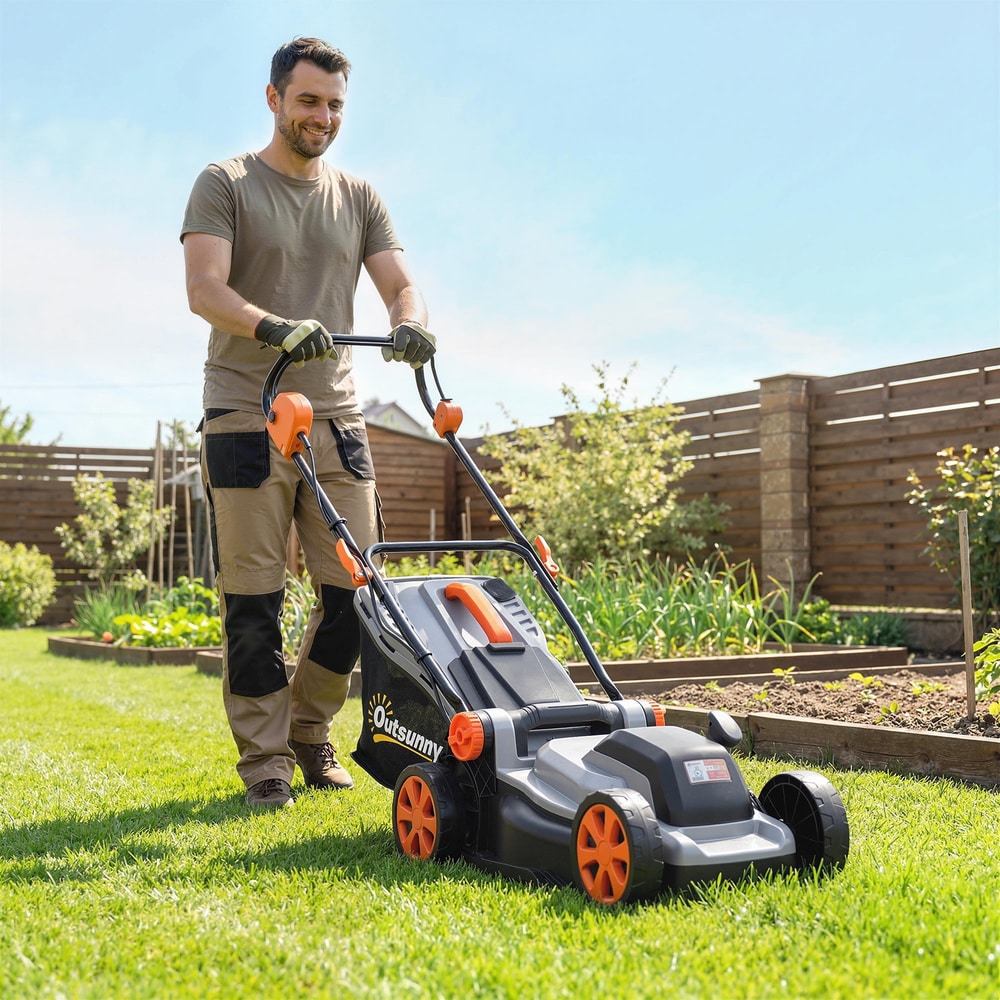 The cordless lawnmower being pushed by a man across a green garden lawn on a sunny day