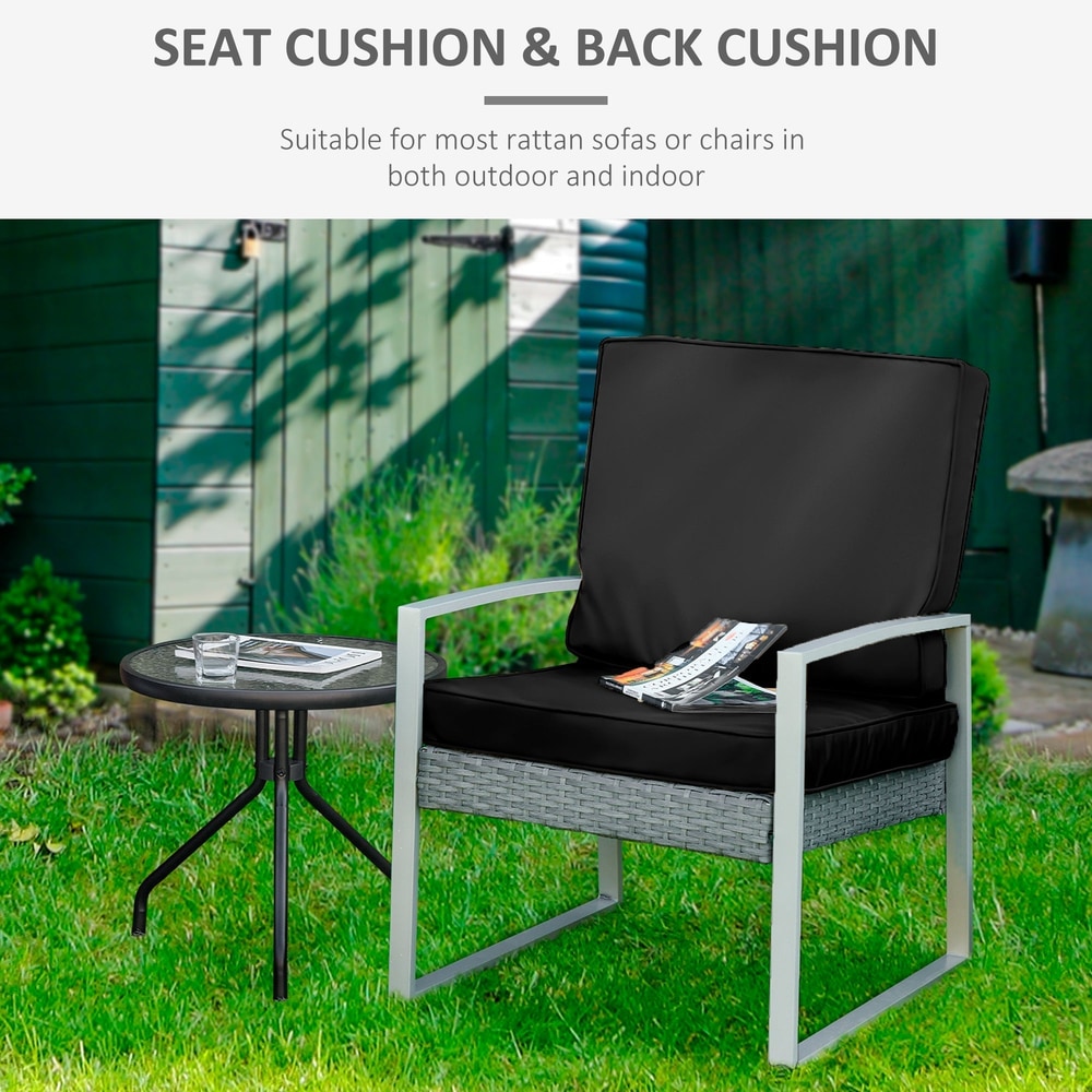 Black outdoor seat pads on a rattan sofa chair in a garden setting