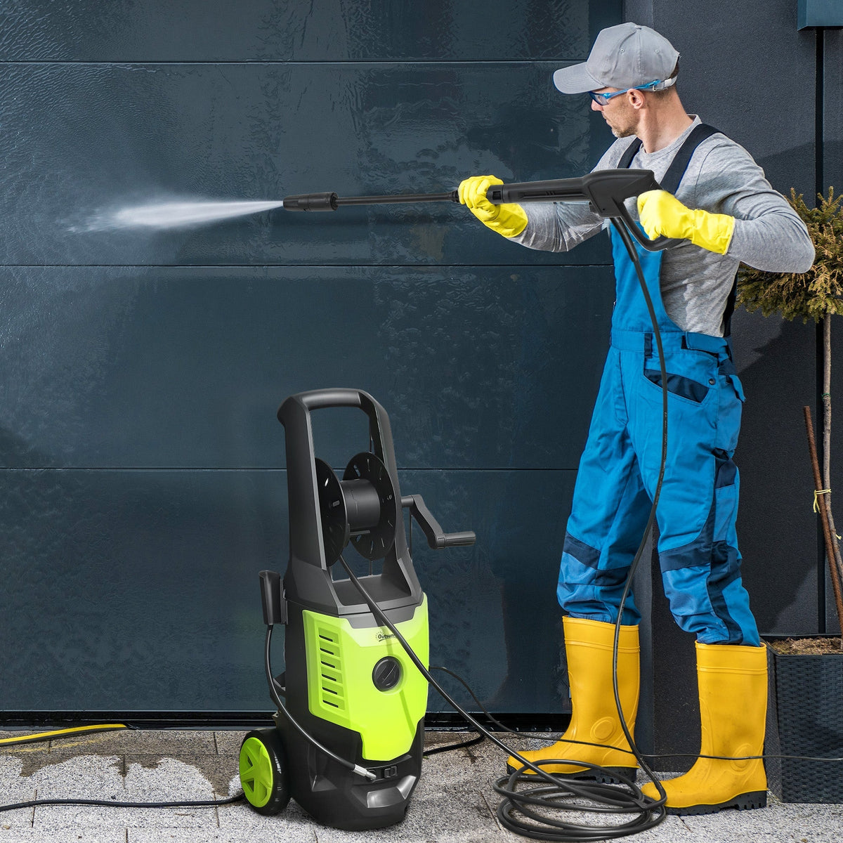 The electric power washer being used by a person to clean a dark garage door