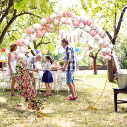A round metal wedding arch decorated with balloons and flowers at an outdoor party