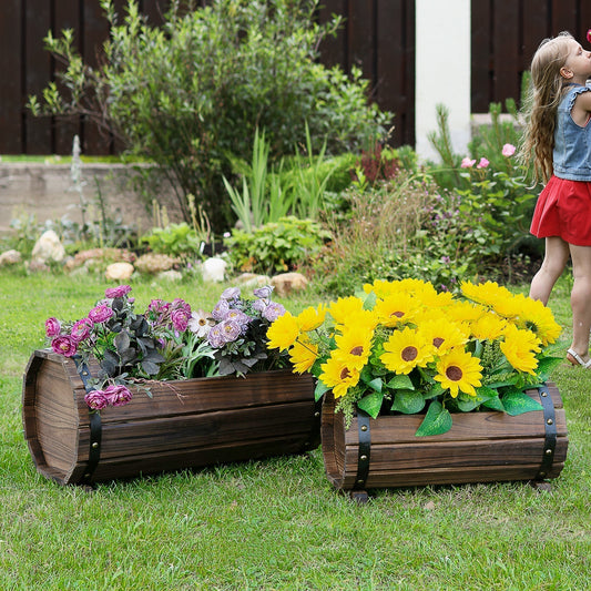 Two wooden barrel planters filled with flowers in a garden setting