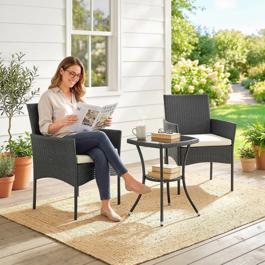 A woman sits on one of the rattan chairs reading a magazine, with the bistro table beside her on a patio