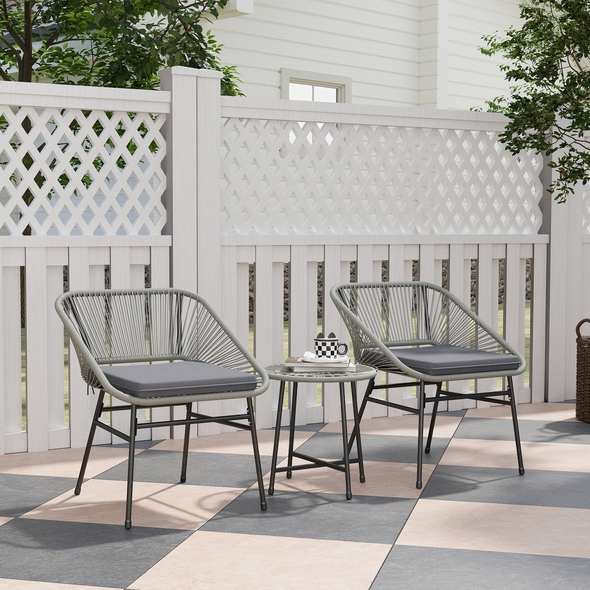 The rattan furniture set placed on a patio with a white fence and greenery in the background