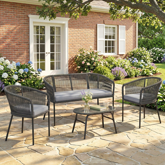 A dark grey rope garden sofa set with a loveseat, two chairs and a glass-topped coffee table on a patio