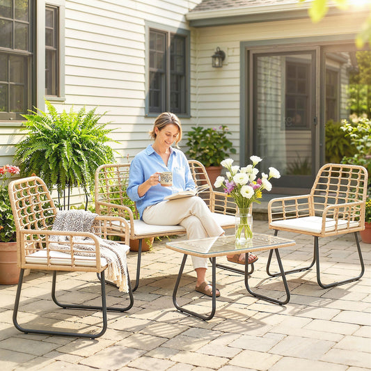 A woman sits on the loveseat of the rattan garden furniture set on a patio