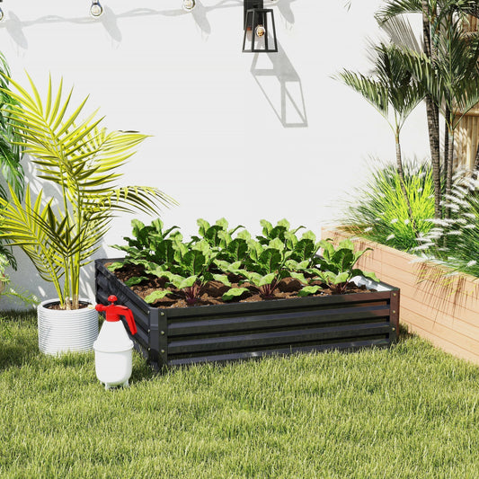 A galvanised raised garden bed filled with young plants and sitting on green grass