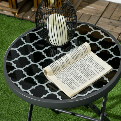 A close-up of the round folding patio table top with a book and candle holder on it