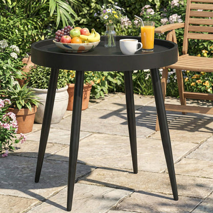 A black round garden table with a fruit bowl and drinks on it, placed on a patio