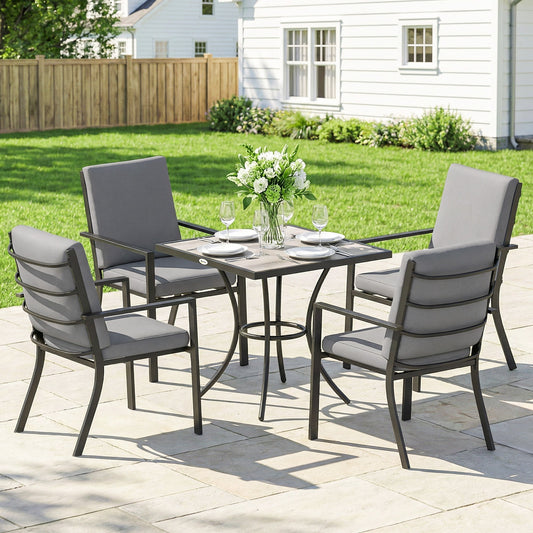 A garden dining set for four people with grey cushions, set up on a patio outside a house