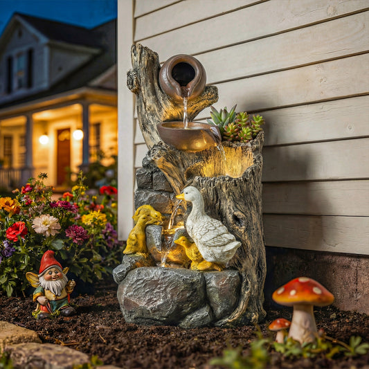 The garden fountain with ducks is lit up at dusk in a garden setting