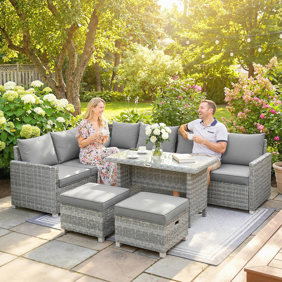 A couple relaxing on the grey rattan furniture set in a garden