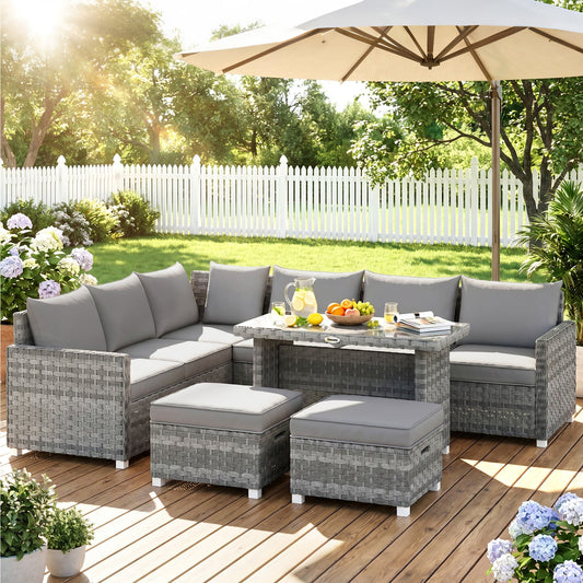The grey rattan garden furniture set arranged on a patio with a parasol overhead