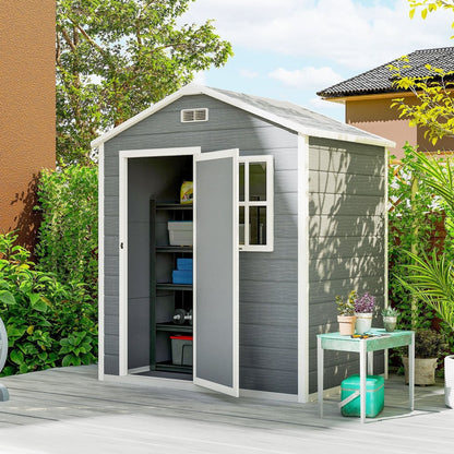 The grey plastic garden shed with its door open showing shelves inside