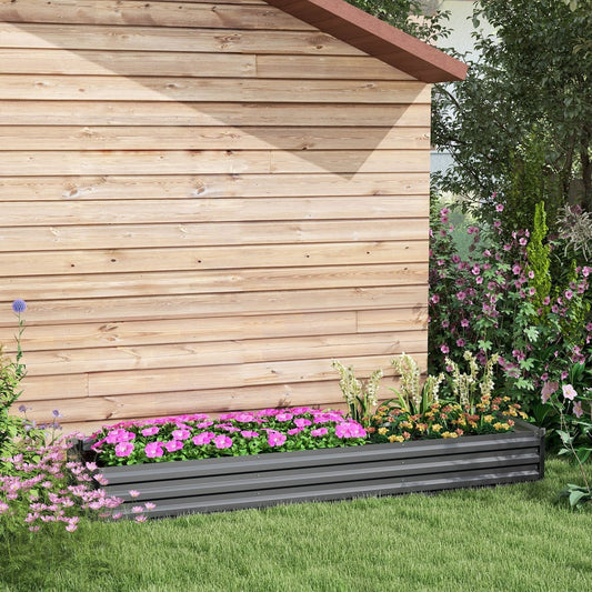 A long galvanised raised garden bed filled with pink flowers sits on green grass next to a wooden shed
