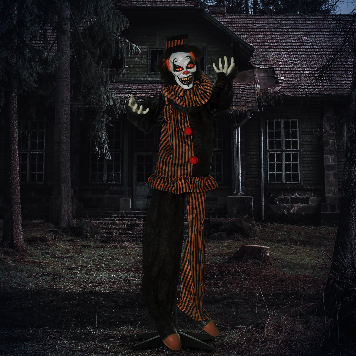 the scary clown decoration standing outside a spooky house at night