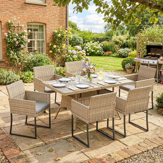Rattan garden furniture set arranged for dining on a patio with a garden in the background