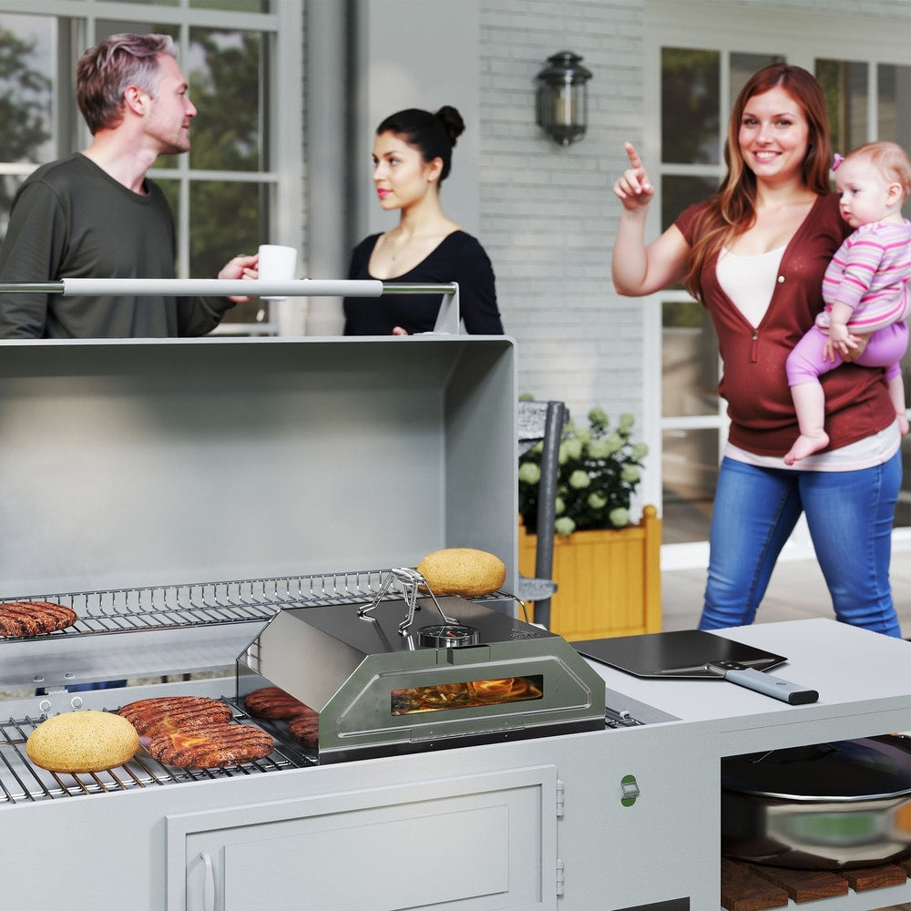 Stainless steel pizza oven on a gas BBQ grill with people in the background