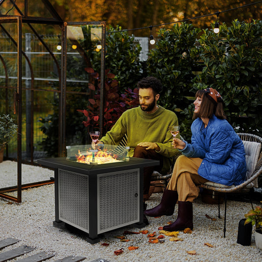 The fire pit lit in a garden setting with a couple sitting nearby holding wine glasses