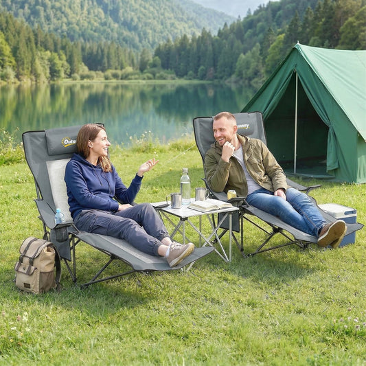 Two people relaxing on camping chairs by a lake with a tent