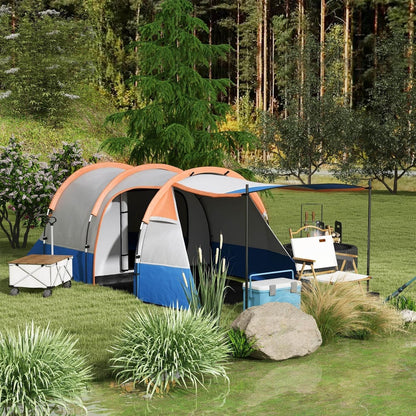 The large tunnel tent set up in a woodland clearing with camping furniture around it