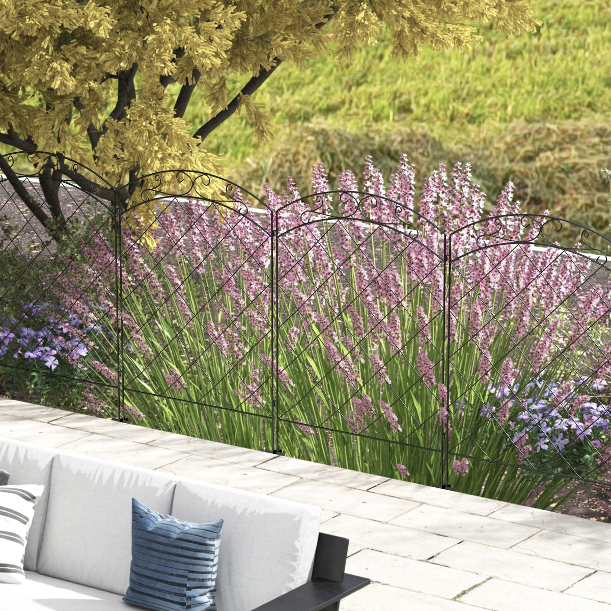 The decorative garden fencing bordering a flower bed with pink flowers and a sofa in the foreground
