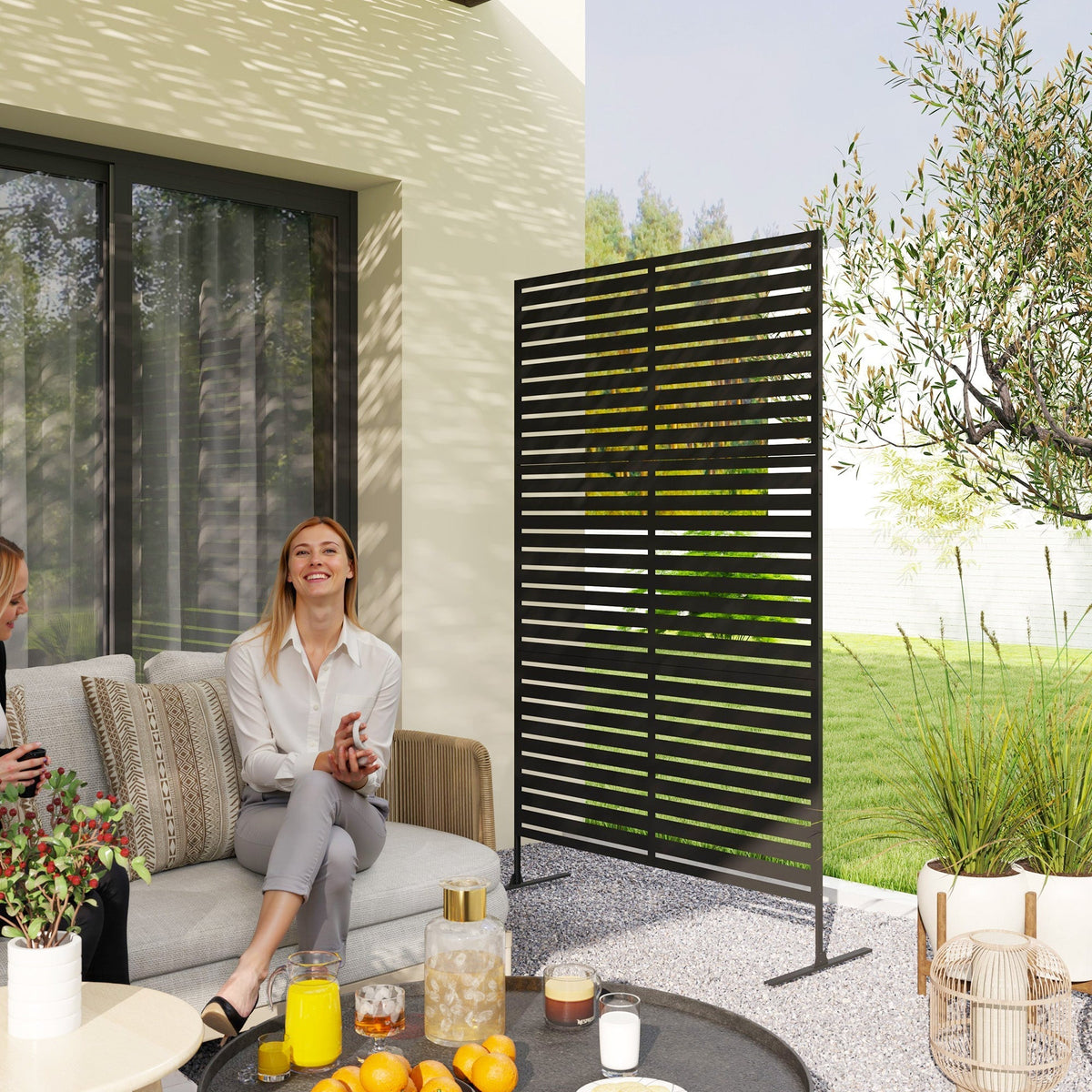 The privacy fence placed on a patio next to a sofa where two women are sitting