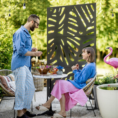 A black metal garden privacy screen with a leaf pattern used outdoors to divide a seating area