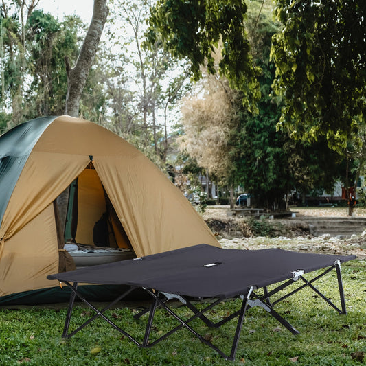 The double camping cot bed set up outside a tent in a grassy area